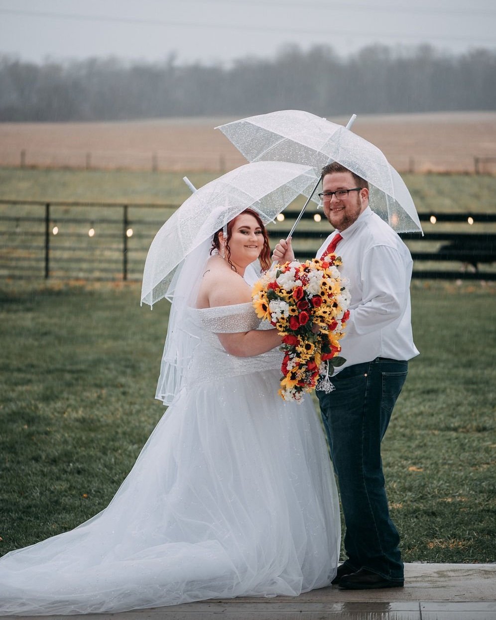 bride and groom in a country rainstorm with umbrellas