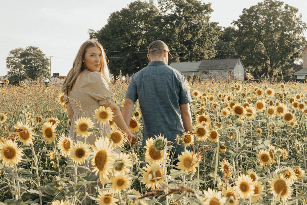 A couple walking hand in hand through a sunflower field