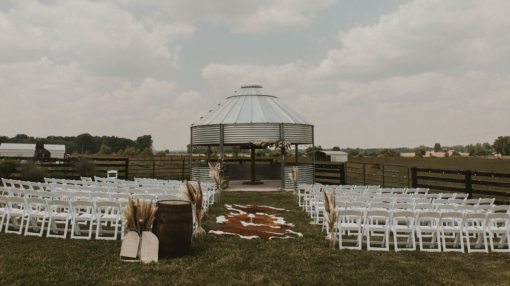 Western-bohemian wedding ceremony setup with grain silo gazebo