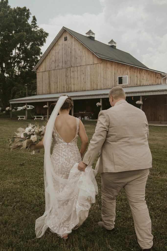 A bride and groom walking through the barnyard at 22 Acres Farm and Venue outside Columbus, Ohio