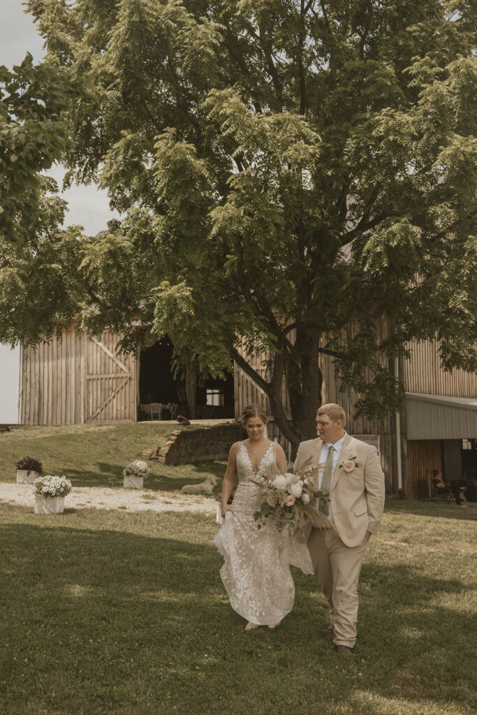 A bride and groom walking through the barnyard at 22 Acres Farm and Venue outside Columbus, Ohio