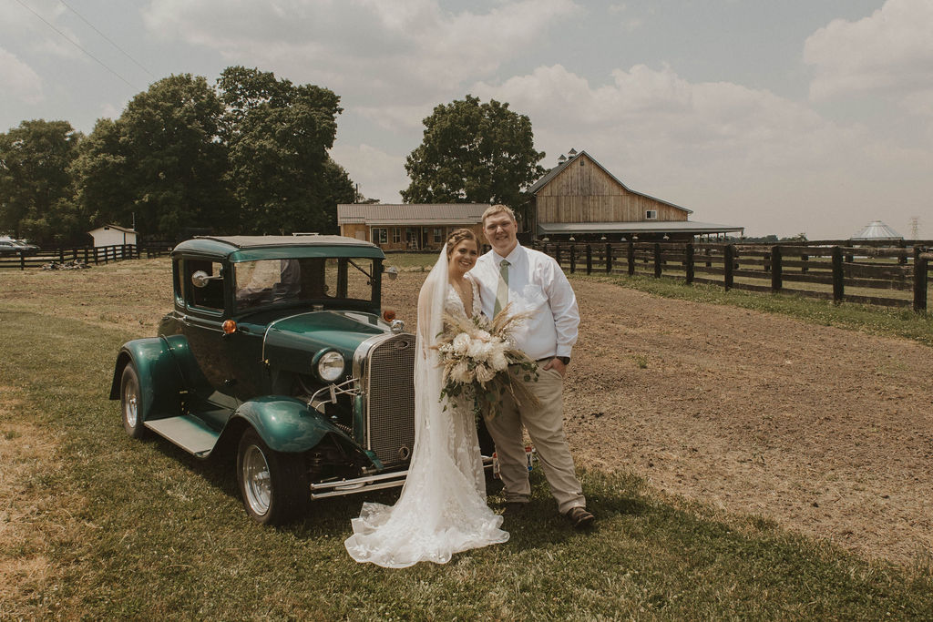 bride and groom and an antique car outside the 22 Acres Farm barnyard near Columbus, Ohio.