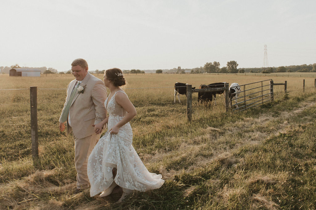 A bride and groom walking through the fields surrounding 22 Acres Farm