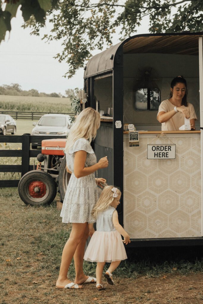 A mother and a child standing next to a beverage truck