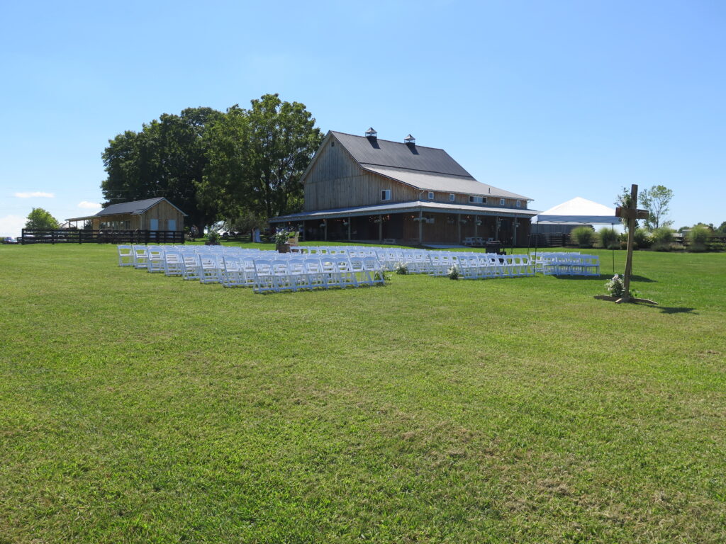 Outdoor wedding ceremony setup at a beautiful venue in Columbus, Ohio, with chairs arranged for guests, a floral arch, and scenic greenery surrounding the space.