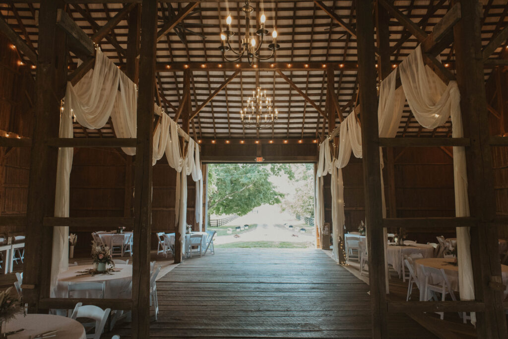 Elegant wedding reception setup at 22 Acres Farm, featuring rustic charm with white draping and soft lighting for an intimate and romantic atmosphere.