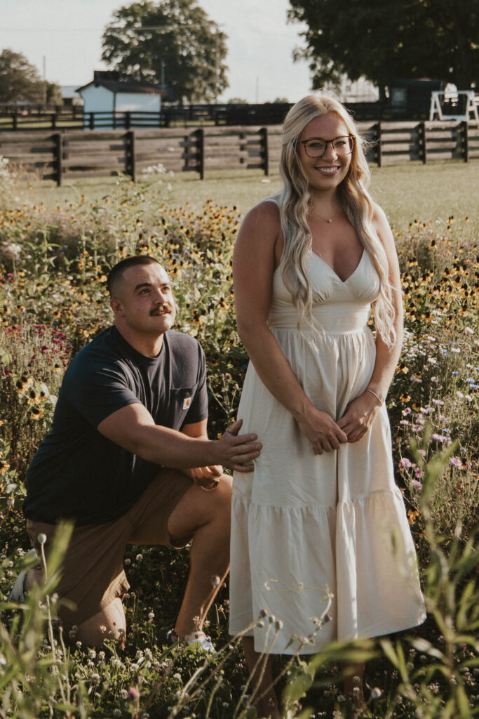 A groom-to-be on one knee proposing in a colorful wildflower field at 22 Acres Farm in Central Ohio.