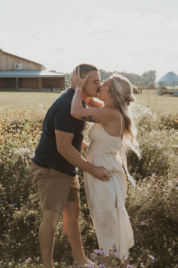 A couple sharing a kiss in a stunning wildflower field moments after saying “yes” at 22 Acres Farm.