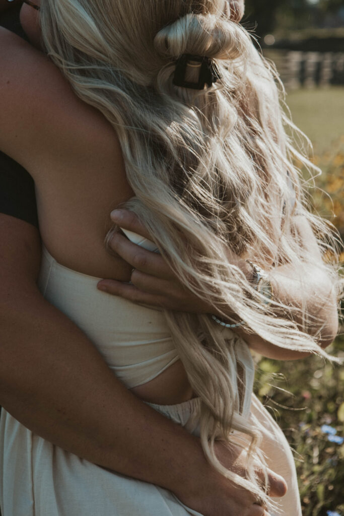 A couple embracing after a surprise proposal among blooming wildflowers at 22 Acres Farm