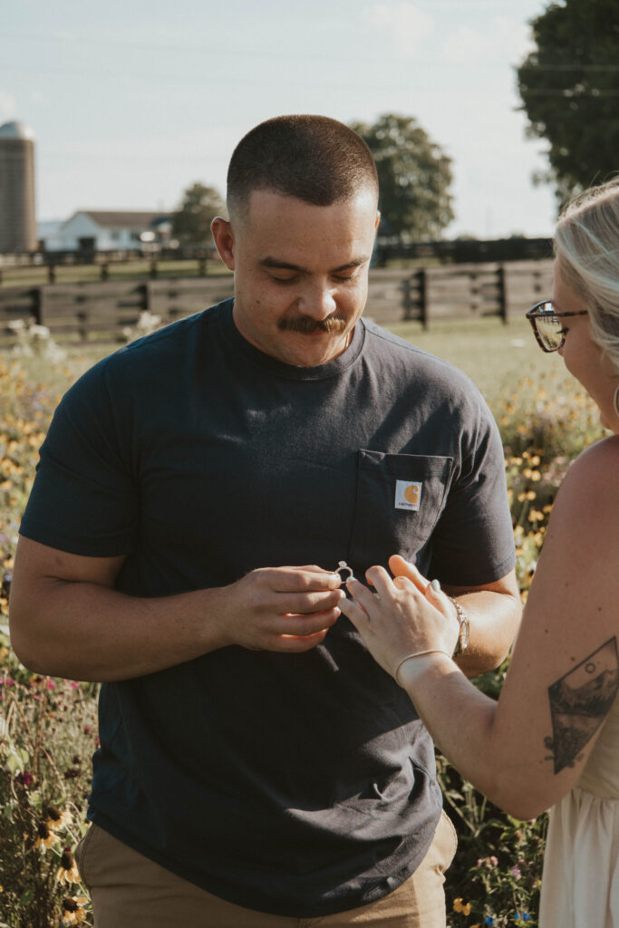 A joyful bride-to-be admiring her engagement ring in a vibrant wildflower meadow at 22 Acres Farm.