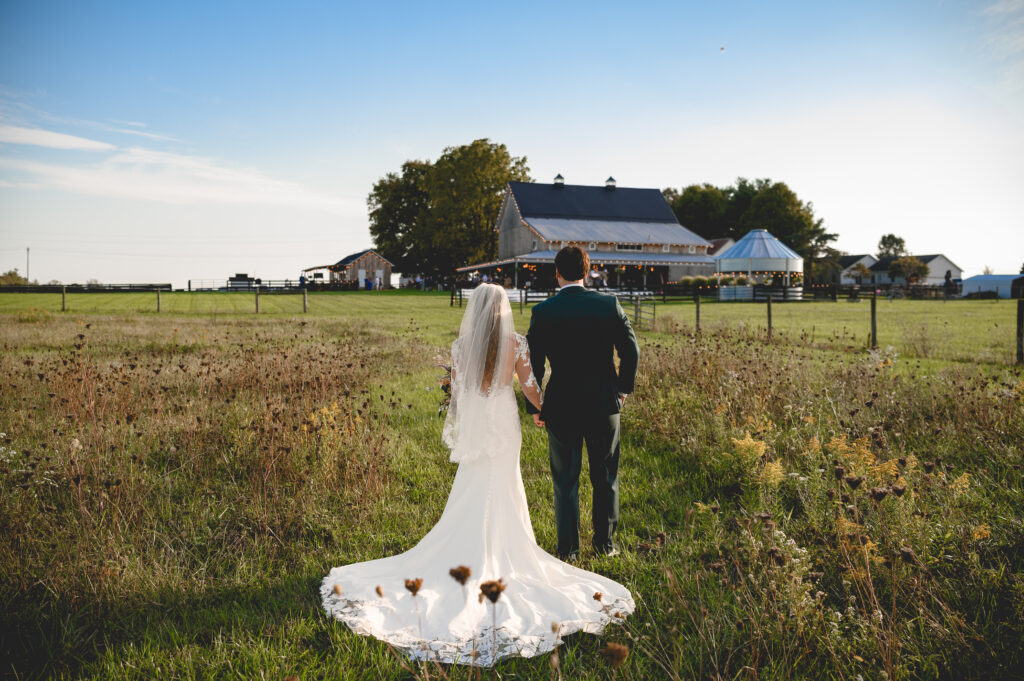 Couple walking through wildflower fields with 22 Acres Farm venue in the background, located near Columbus, Ohio