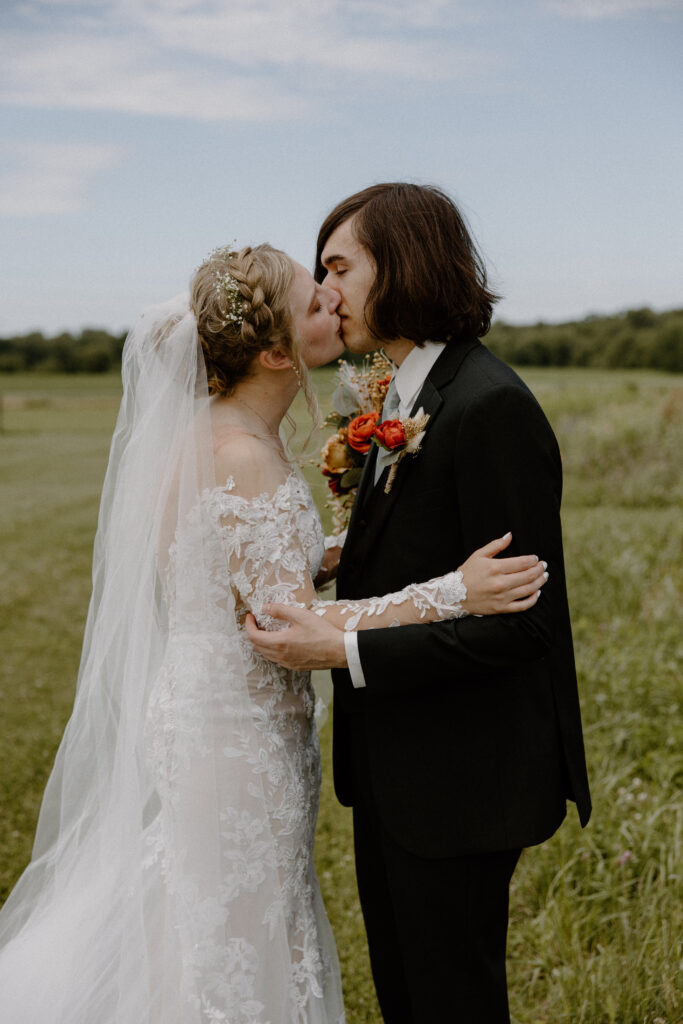 A bride and groom kissing in the fields surrounding Columbus, Ohio’s 22 Acres Farm.