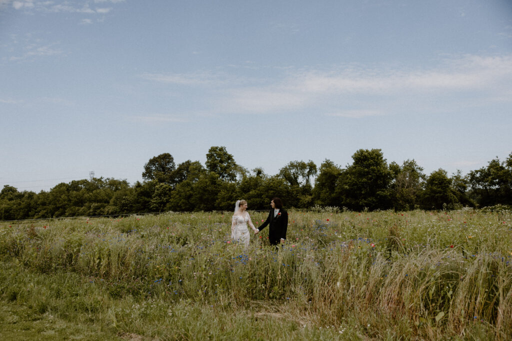 A bride and groom looking across the expansive fields at 22 Acres Farm, a Columbus, Ohio wedding venue.